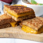 Grilled cheese sandwich cut into pieces stacked on top of each other on a wooden board.