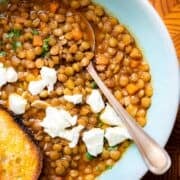 An overhead photo of Mediterranean Lentil Soup. The soup is garnished with goat's cheese, and a piece of toasted bread.