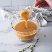 All-Purposes Gravy in a gravy boat, with a big ladle of gravy.