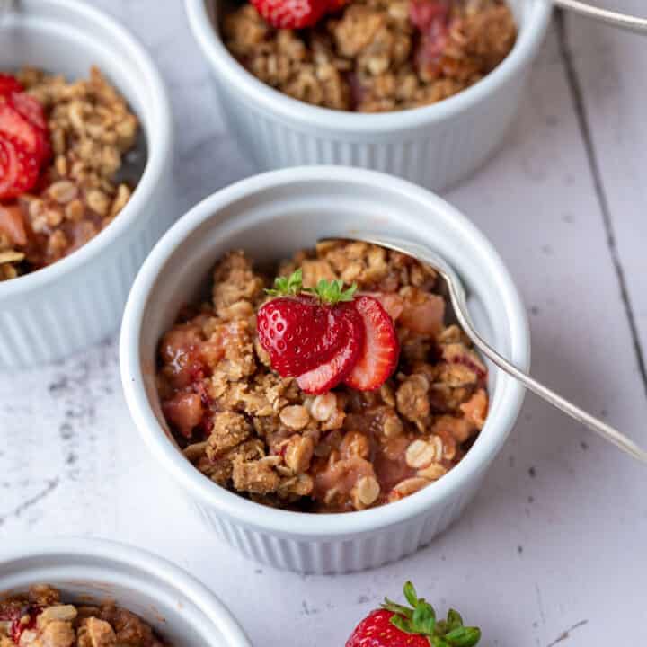 A ramekin filled with strawberry and apple crumble.
