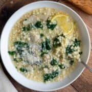 A bowl of pastina egg drop soup garnished with grated parmesan cheese.