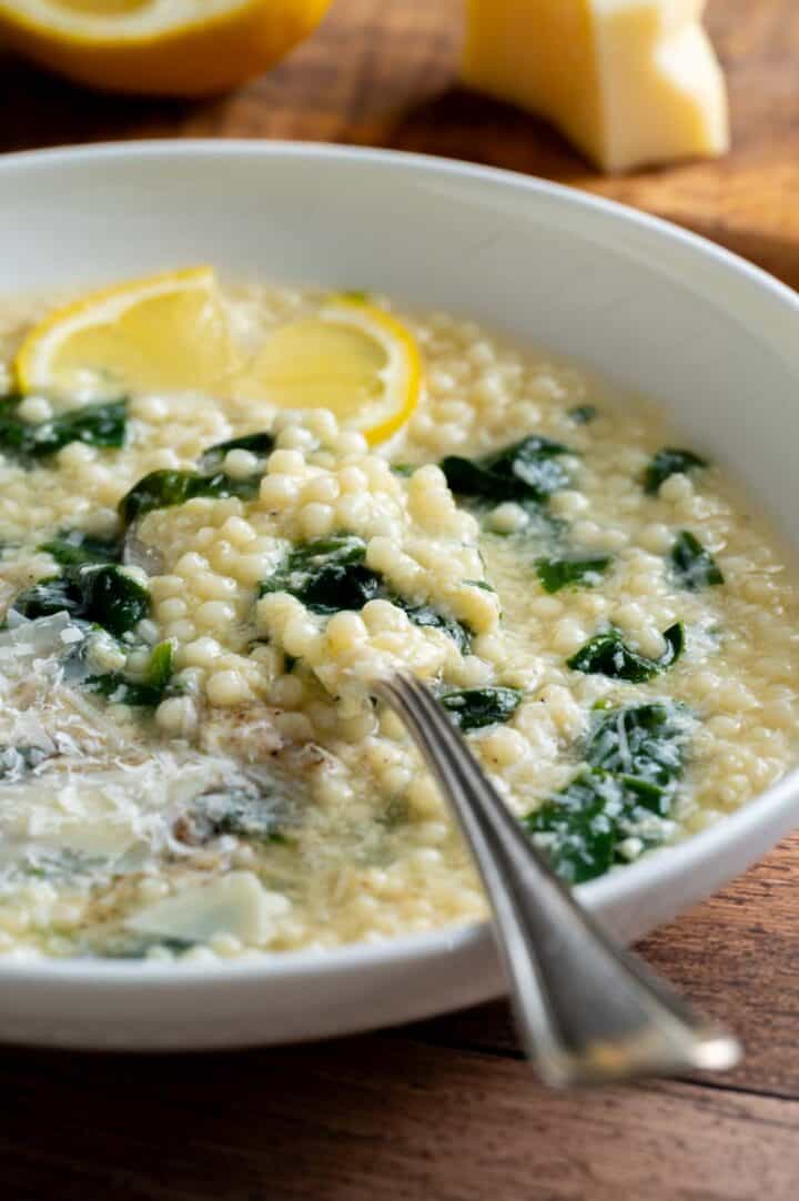 A bowl of pastina egg drop soup served in a bowl and garnished with parmesan cheese.