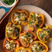 A round casserole dish with cooked bison stuffed bell peppers.