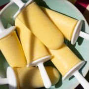 Frozen yogurt mango popsicles on a plate ready to serve.