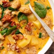 A bowl of white bean soup with sausage and potatoes.