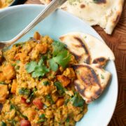 A plate of red curry lentils with sweet potatoes and spinach.