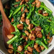 A skillet with cooked sausage and rapini.