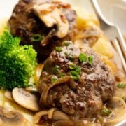 Hamburger steaks with onion and mushroom gravy in a plate.