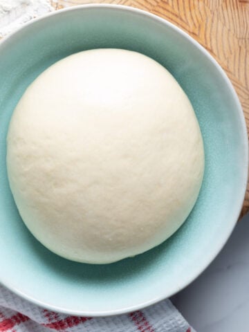 Same-day pizza dough ball in a shallow bowl.