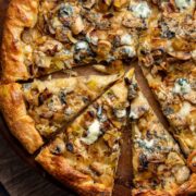 A cooked blue cheese, mushroom and leek pizza, cut into triangles ready to serve.
