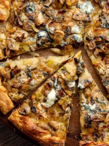 A cooked blue cheese, mushroom and leek pizza, cut into triangles ready to serve.