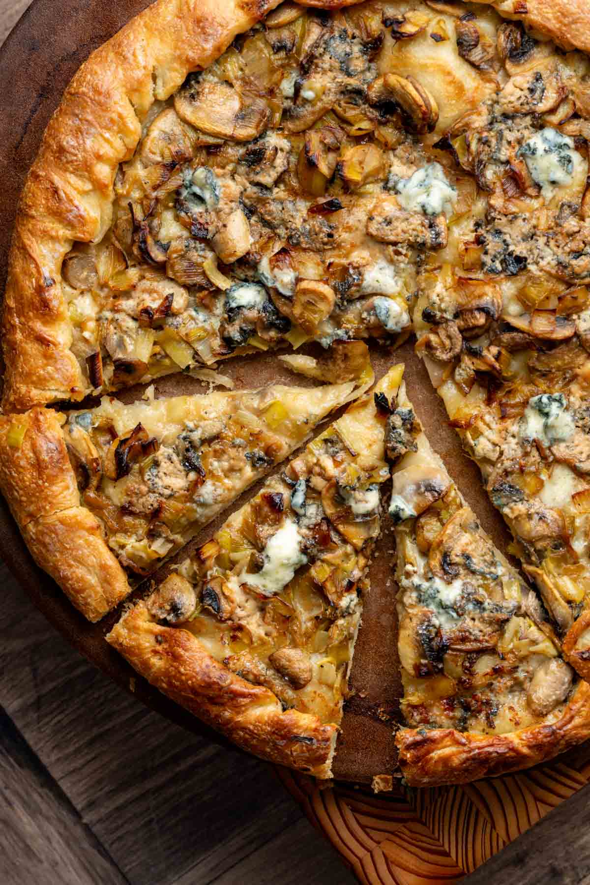 A cooked blue cheese, mushroom and leek pizza, cut into triangles ready to serve.
