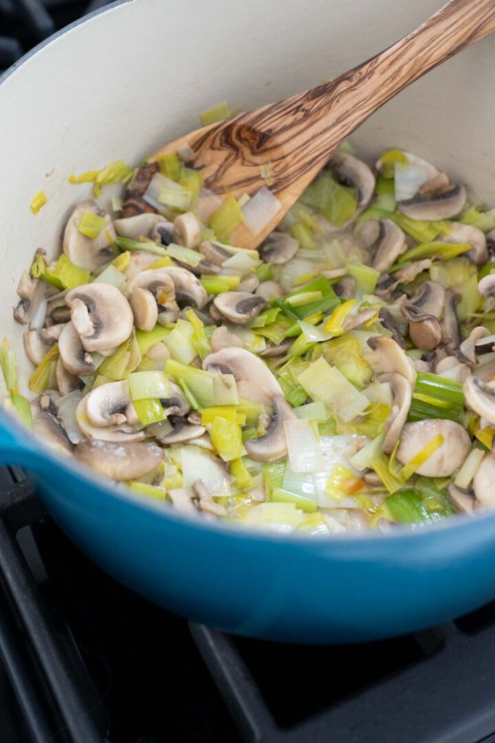 Frying mushrooms and leeks in a large Dutch oven.