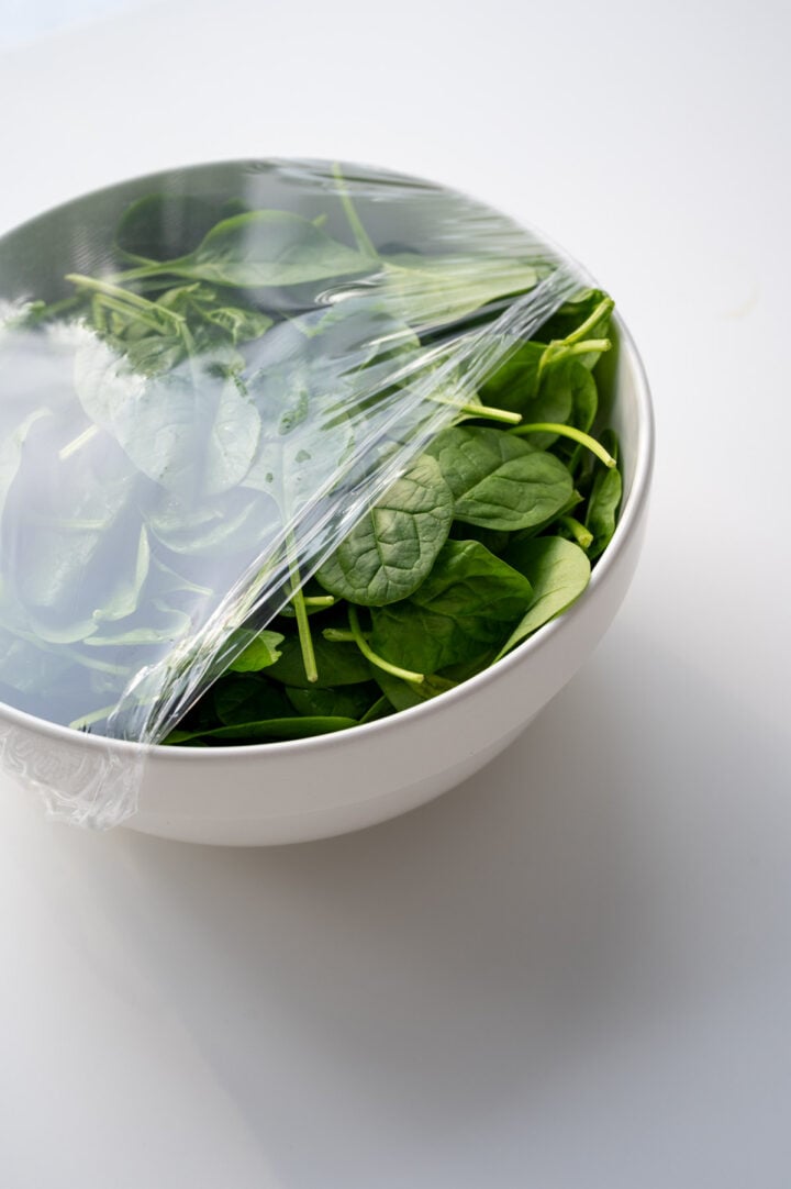 Uncooked spinach in a large bowl.