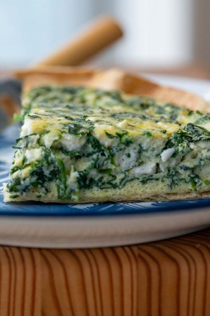 A slice of spinach and feta quiche on a plate.