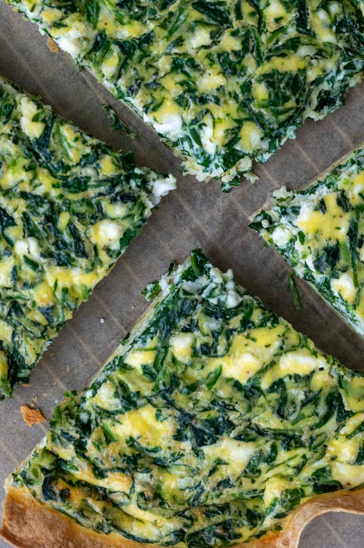 A spinach and tortilla quiche cut into four equal pieces.