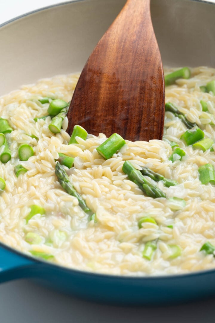 A skillet with lemony orzo, asparagus and peas.