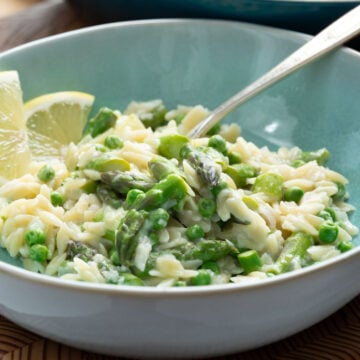 A bowl of lemony orzo with asparagus and peas.