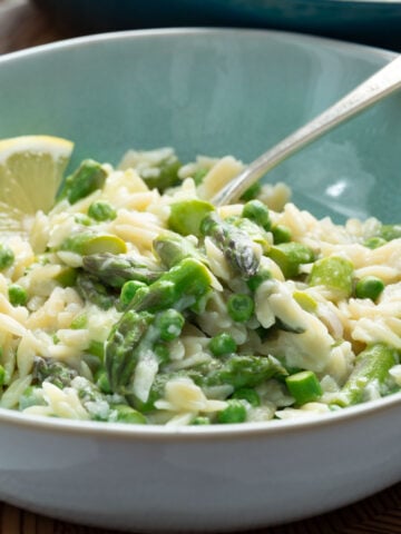 A bowl of lemony orzo with asparagus and peas.