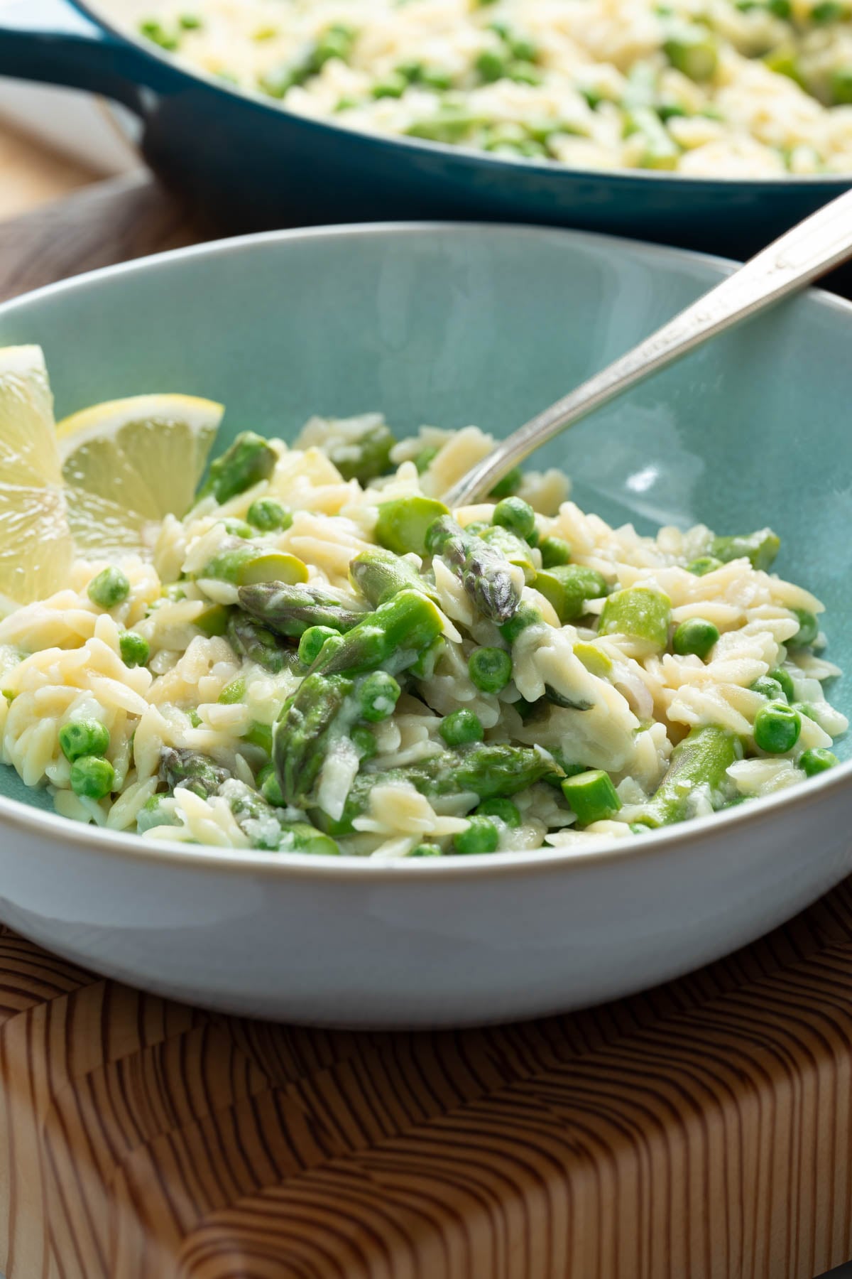 A bowl of lemony orzo with asparagus and peas.