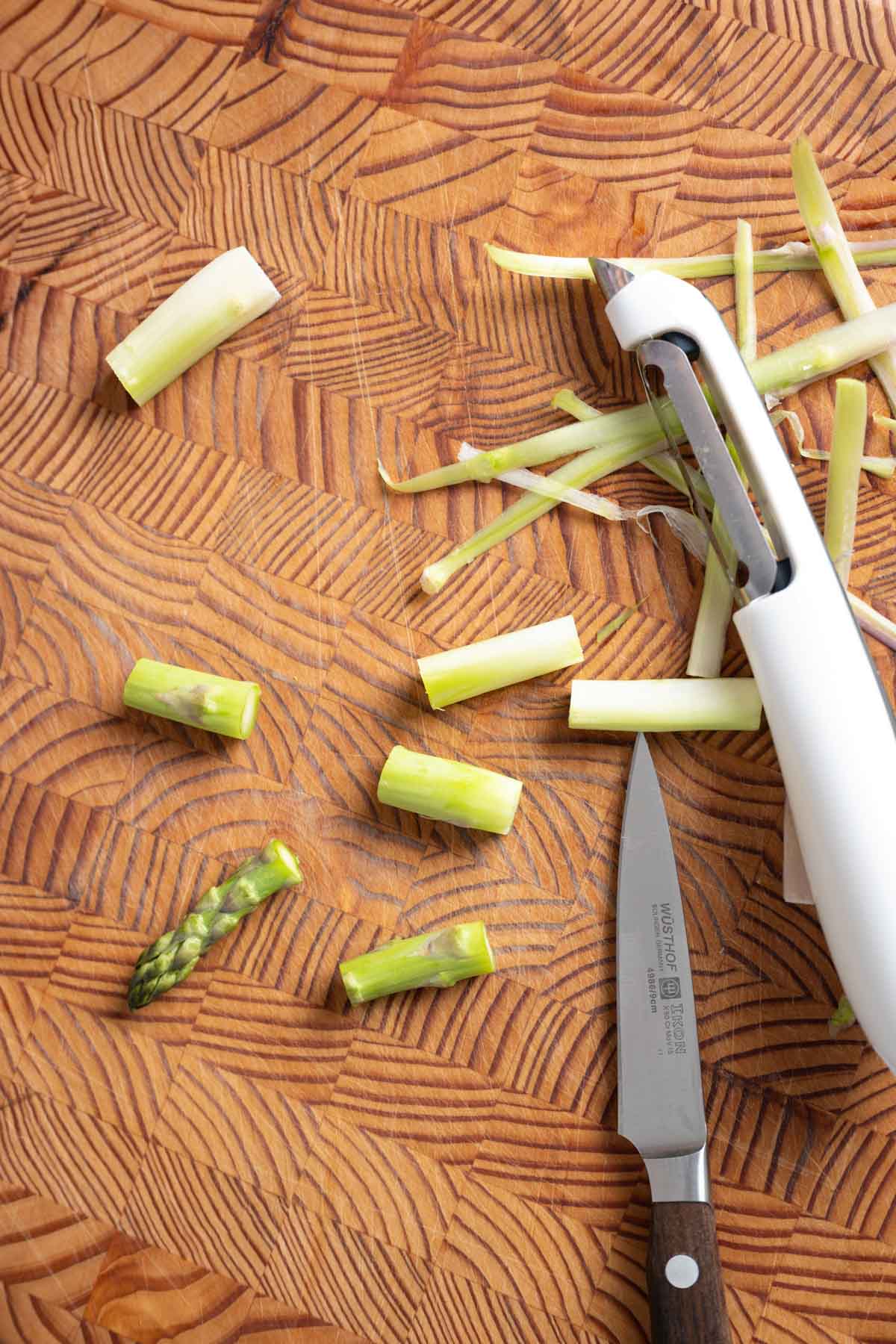 Cut asparagus spears on a wooden cutting board.