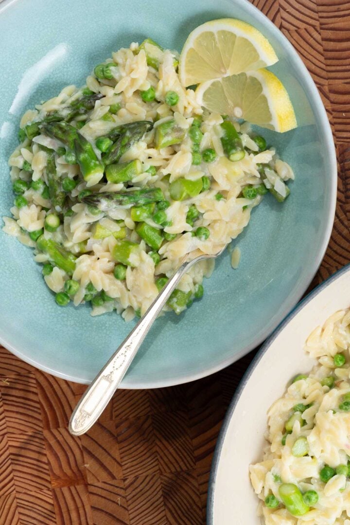 A bowl of lemony orzo with asparagus and peas.
